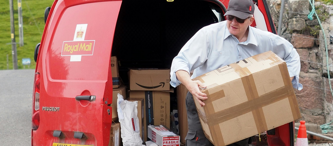 Elderly postman taking a parcel out of a van