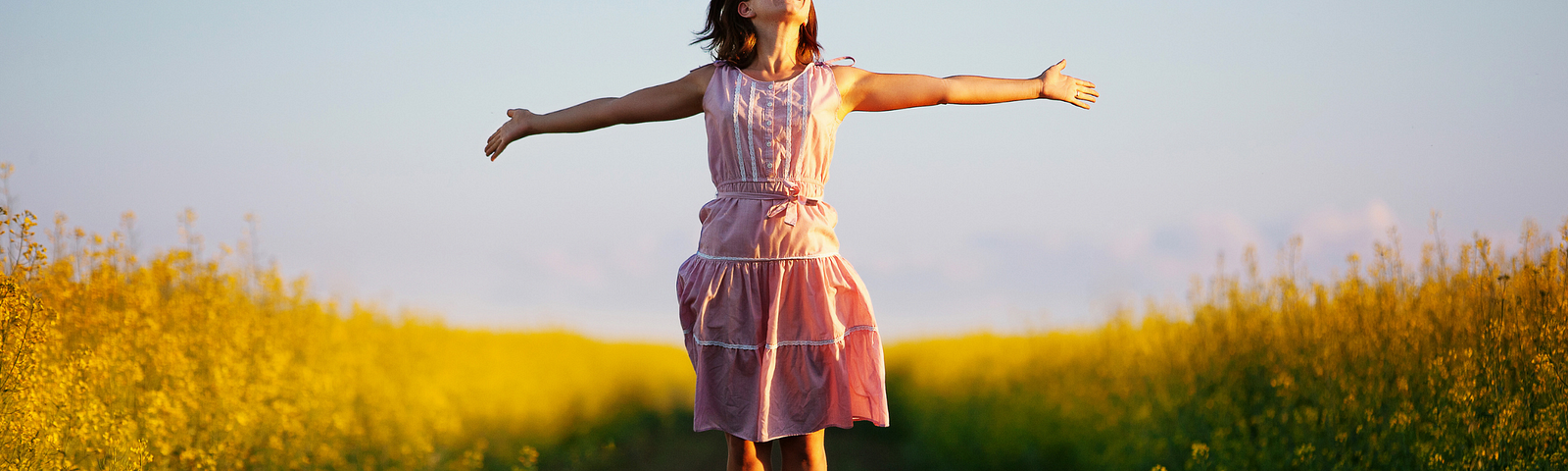 A happy girl stretching arms in a field