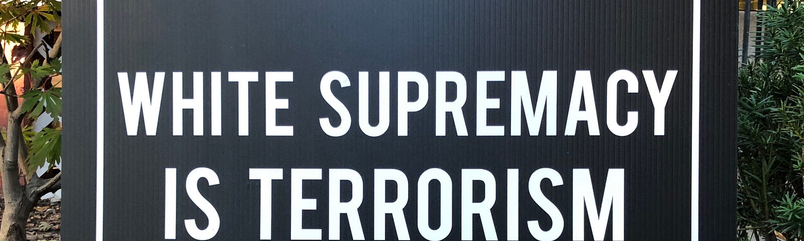 Lawn sign, white text on black background, that says “White Supremacy is Terrorism” in all caps.