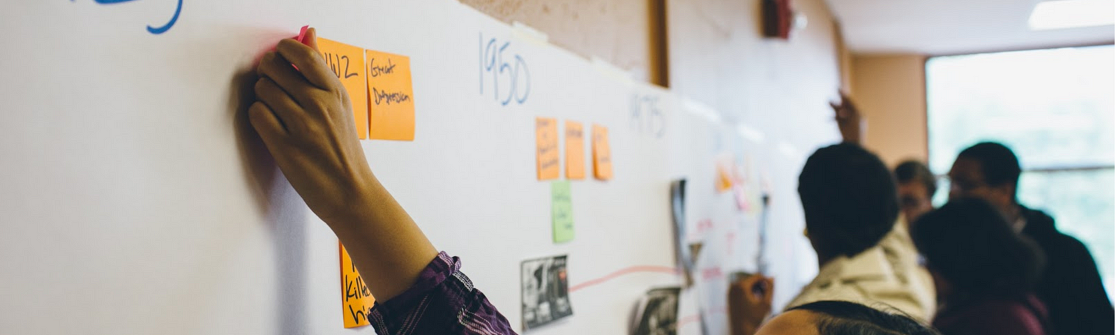 Youth girl placing a post-it note on a large timeline with the years 1925 and 1950 displayed