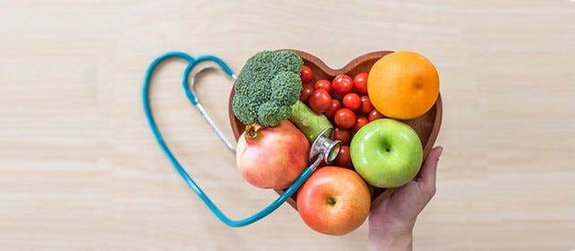heart shaped bowl filled with fruits & veggies and stethoscope in the shape of a heart