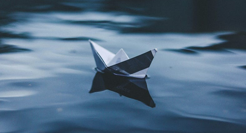 An origami boat sitting on water.