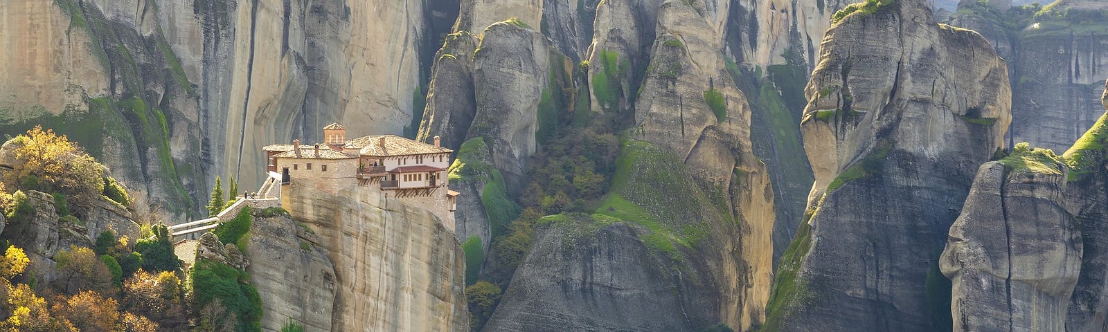 A Greek monastery on a mountainside, ringed by mountains.