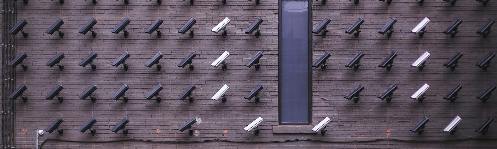 Two people look up at dozens of security cameras along a build