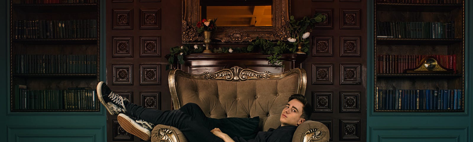 A casually dressed man laying across an expensive sofa