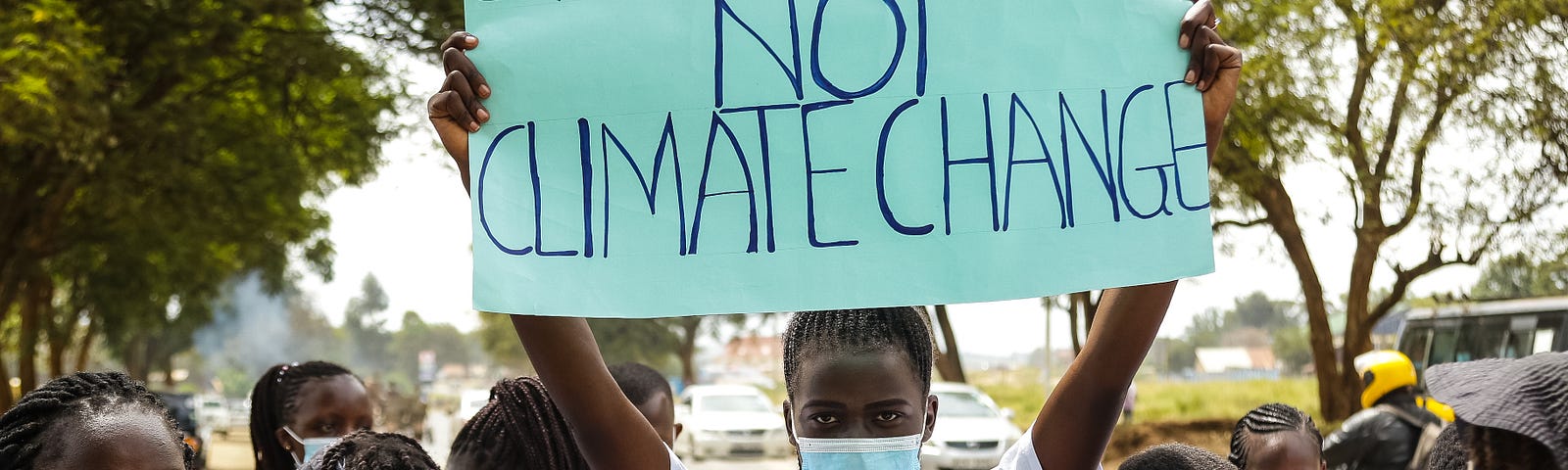 A climate activist holds a sign that reads ‘System change not climate change’ above a protest.