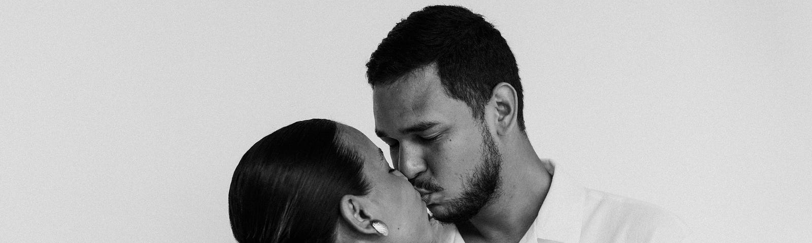 A black and white photo of a man and a woman kissing