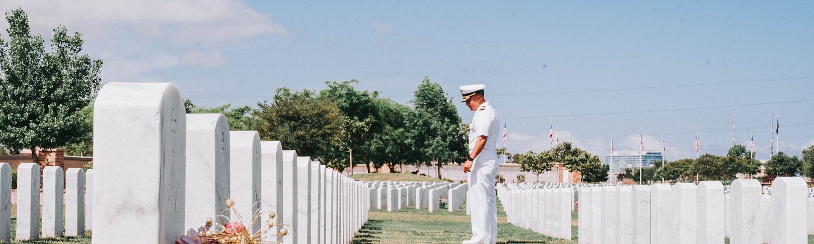 A service member stands in front of a row of tombstones.