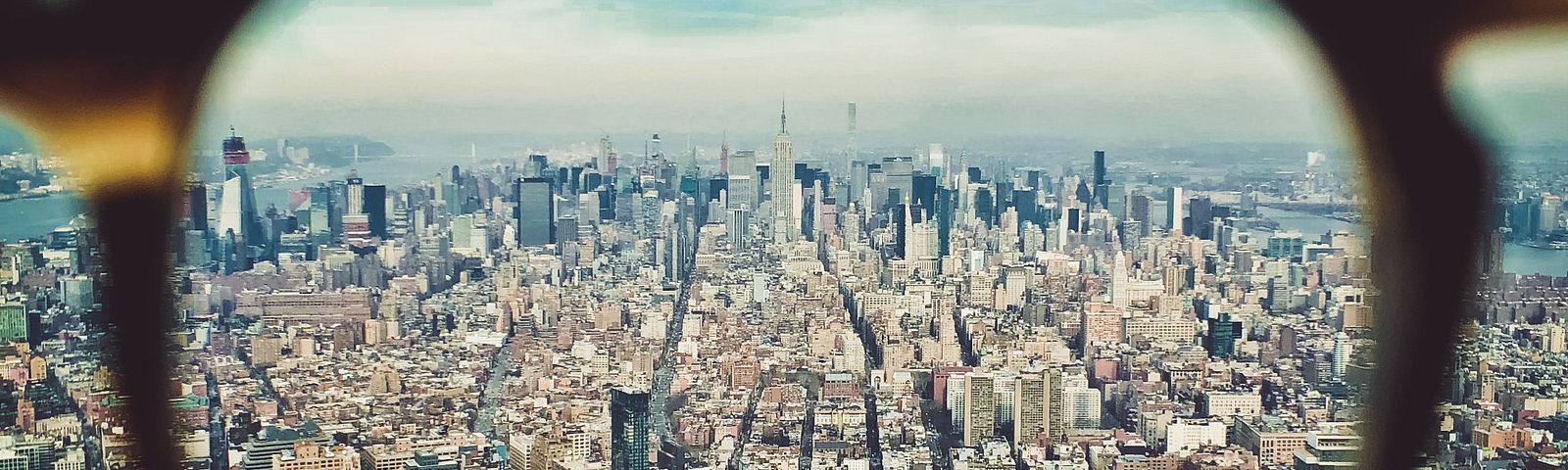 A city landscape is seen through the lens of an eyeglass