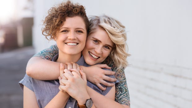 Brunette woman and blond woman hugging.