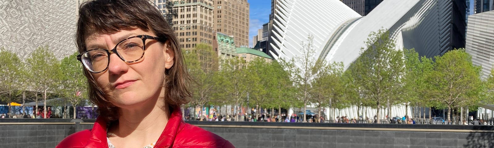 Photo of the author in a red jacket, standing in front of the 9/11 Memorial