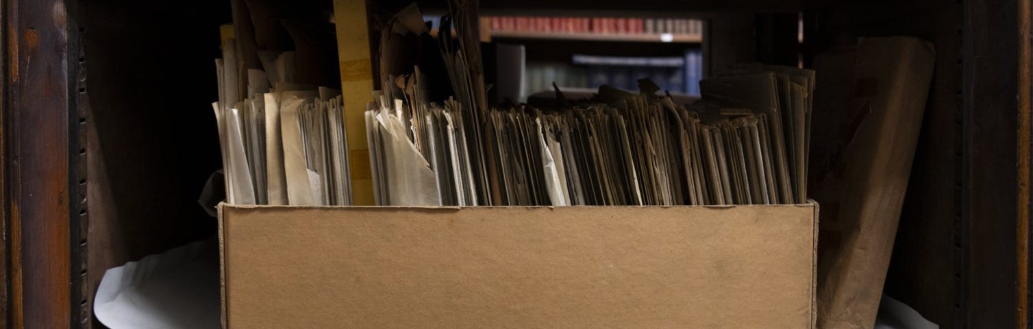 A cardboard box of glass negatives on a shelf in the library basement