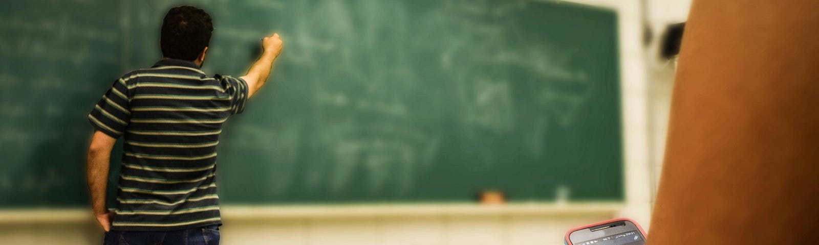 A teacher standing at a chalk board.