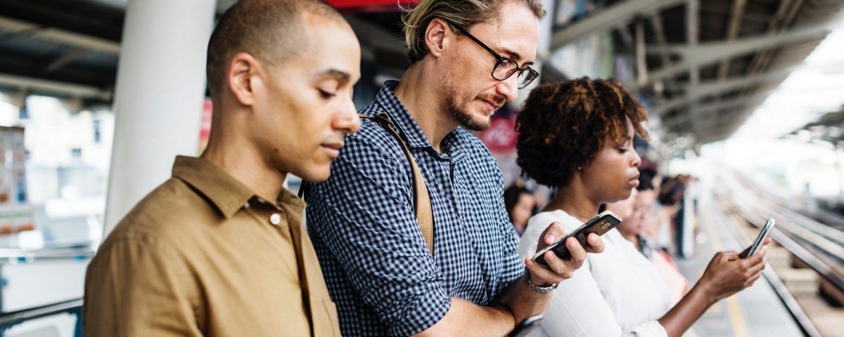 People using smart phones at a train station