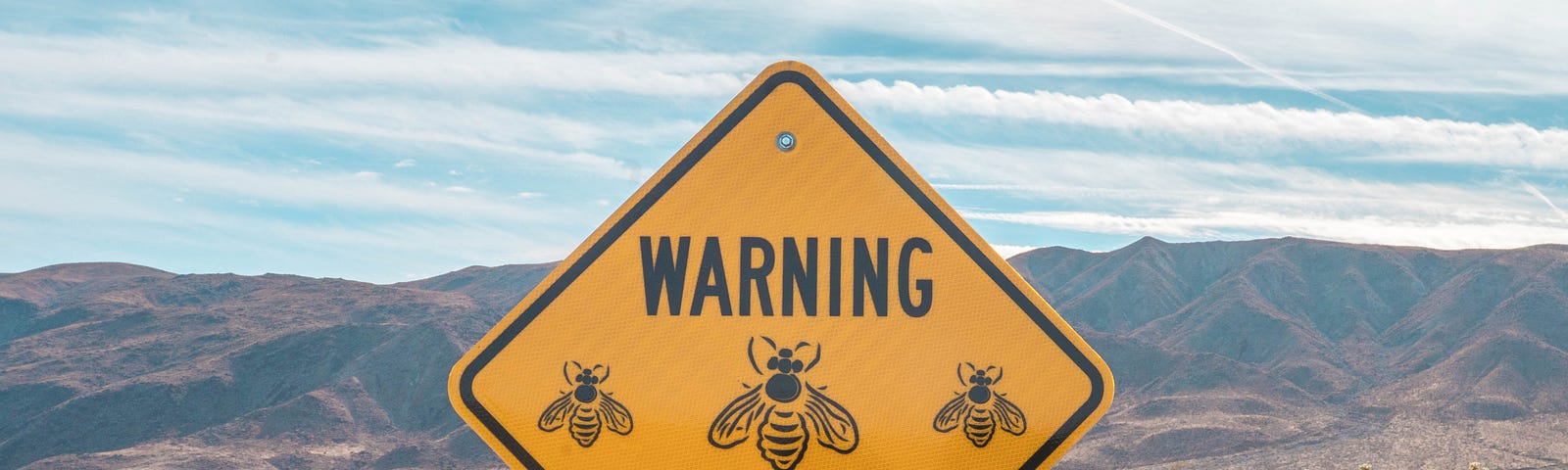 Yield sign with cartoons of bees reads “Warning Ahead”