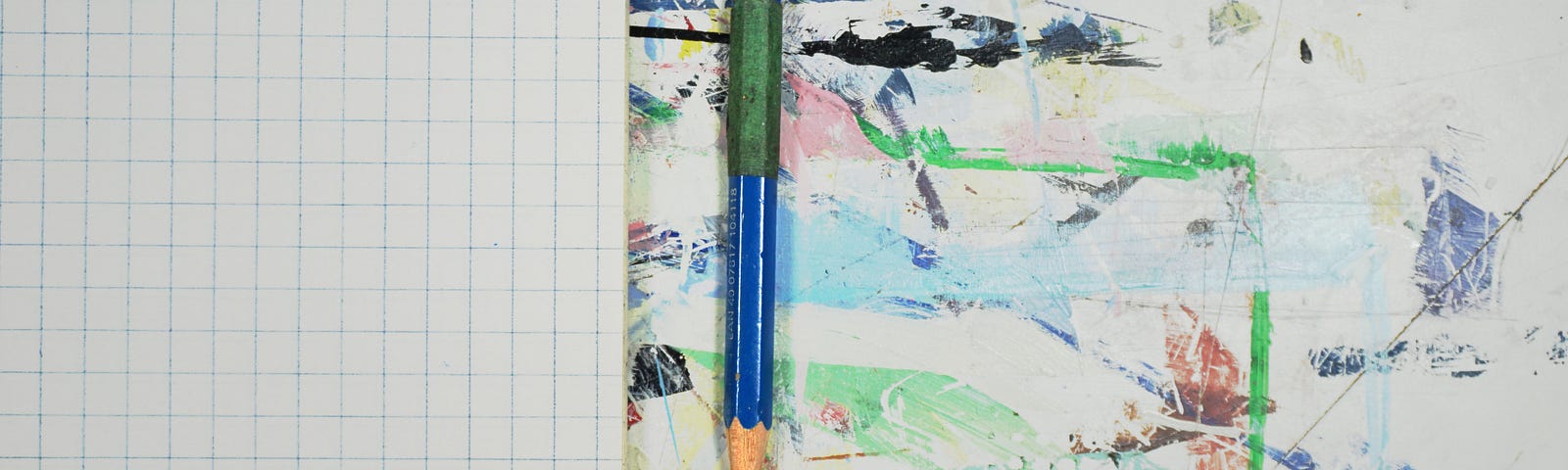 一个空白的格子笔记本摊开在溅满油漆的桌子上，旁边还有一支铅笔。