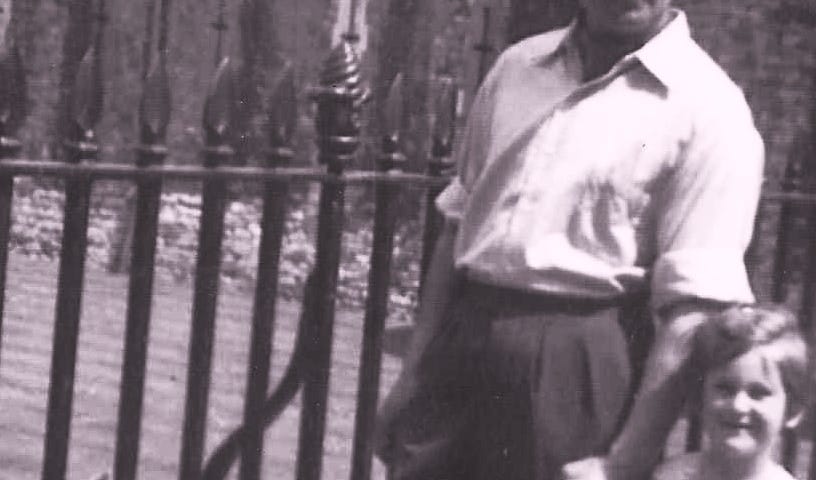 A black and white family photo of the author as a very young girl in a cotton dress walking hand in hand past an iron fence with her father; white shirt, sleeves rolled up, long dark trousers.