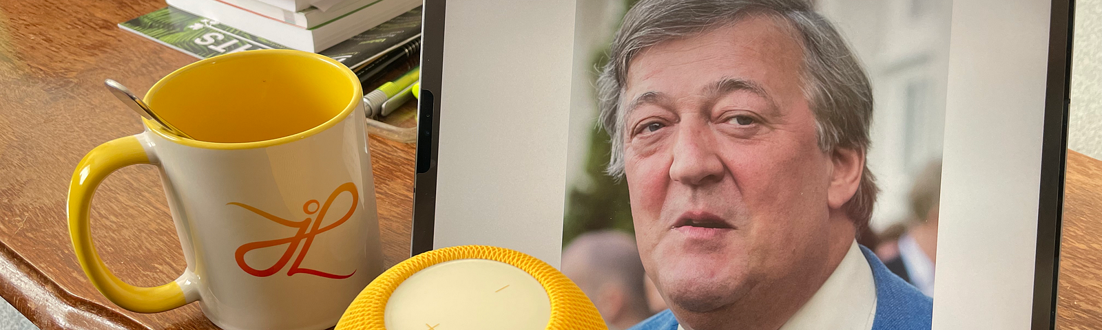 A teacup, Apple’s HomePod mini and a photo of Stephen Fry on a table.