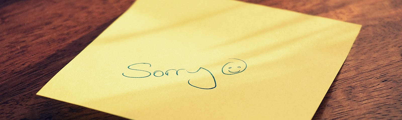 A post-it note saying “sorry” with accompanying smiley face in Biro.