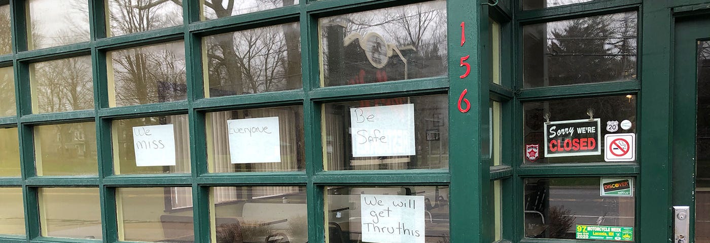 A restaurant remains closed in Upstate New York. Handwritten signs of optimism are taped to the windows.