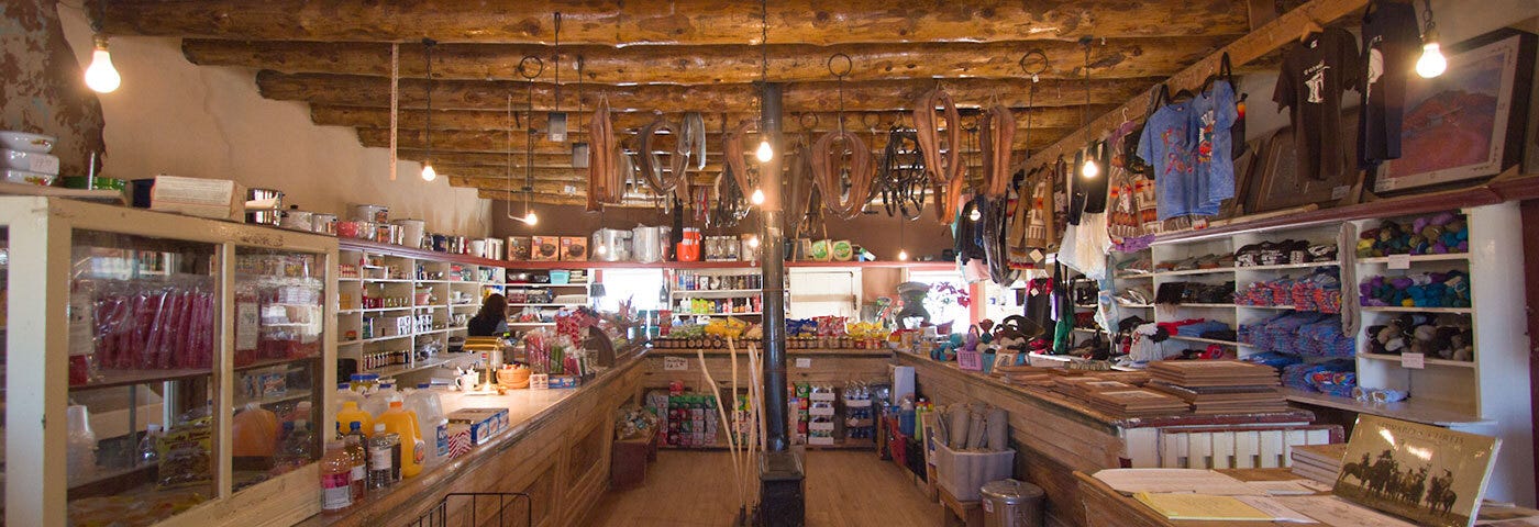 Interior of a trading post in Arizona, with wooden floor and ceiling with various Indigenous artifacts on the walls.