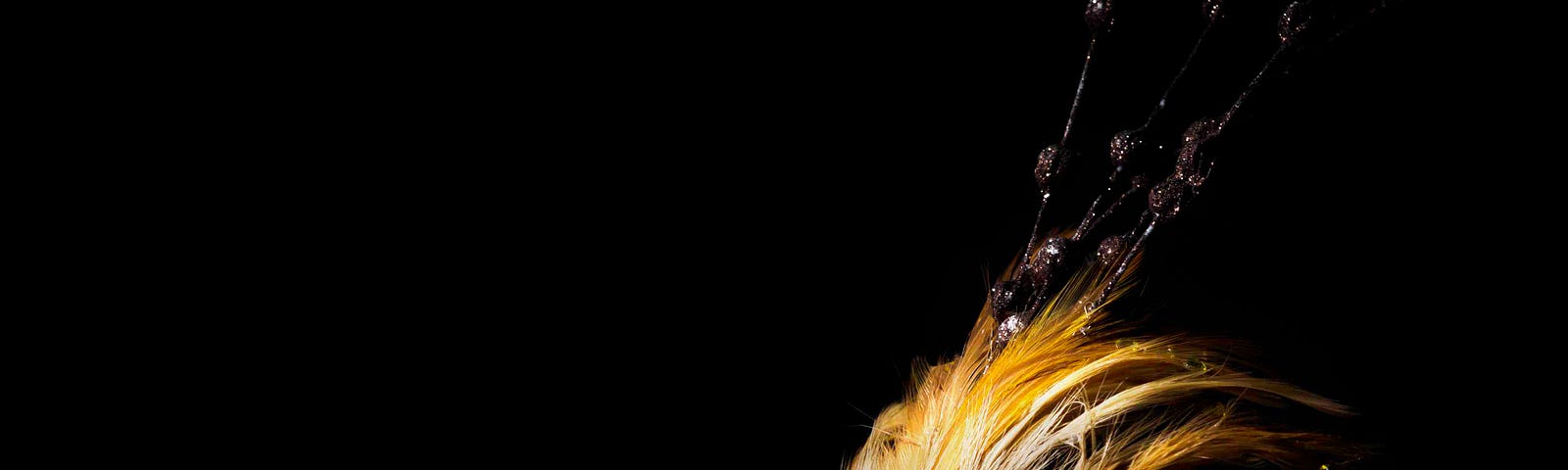 A golden Venetian mask against a background of black.