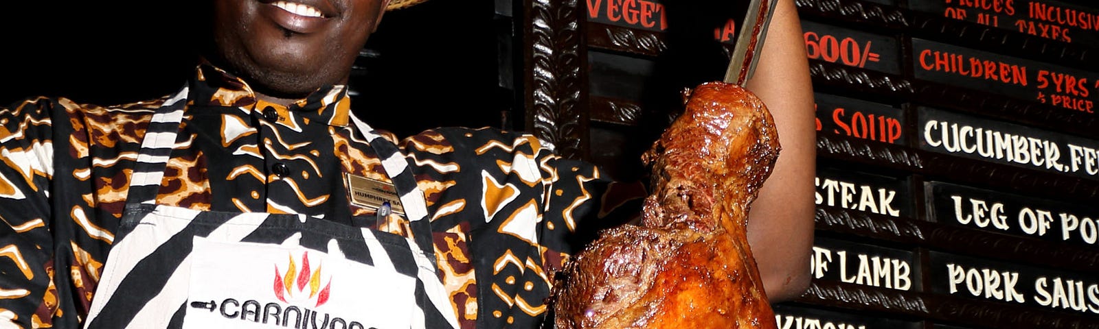 A restaurant worker at The Carnivore Restaurant is shown slicing meat on a sword