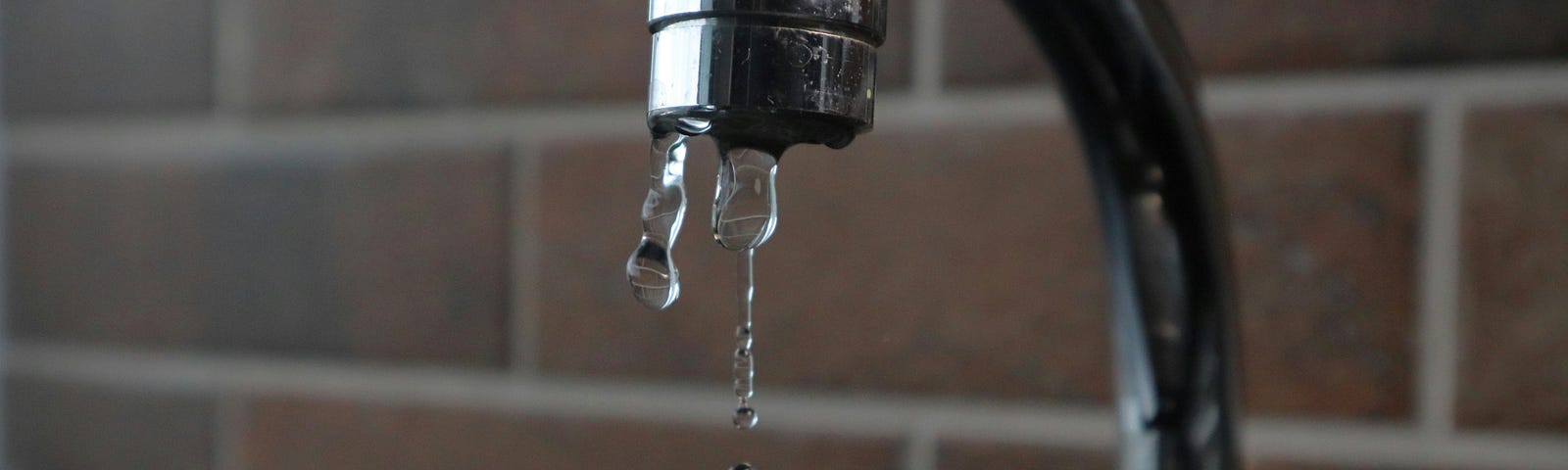 Tarnished silver faucet leaking water.