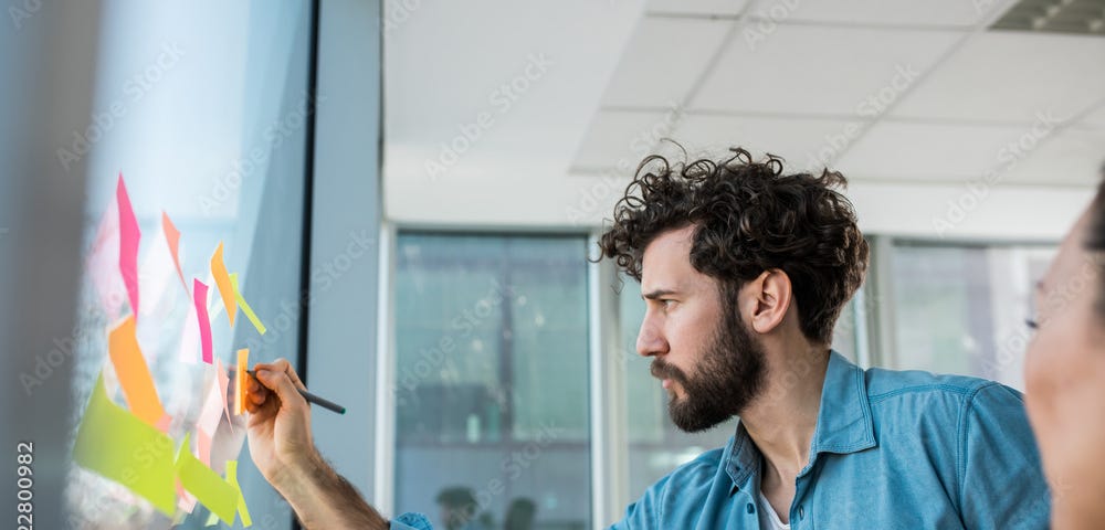 Man writing on a Post-It again a glass wall