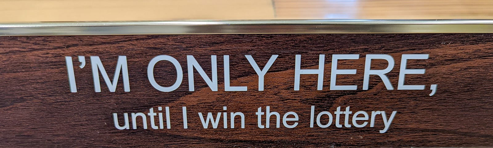 Desk placard reading “I’M ONLY HERE, until I win the lottery”. That’s one strategy, sure