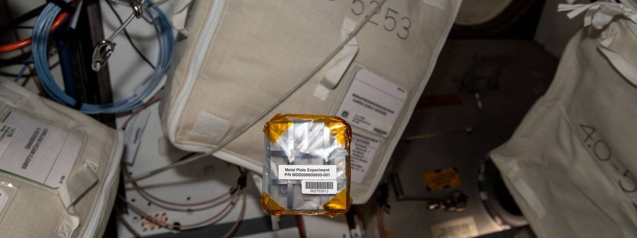 The Project Ascension pack of 25 Titanium plates wrapped in plastic floats aboard the International Space Station.