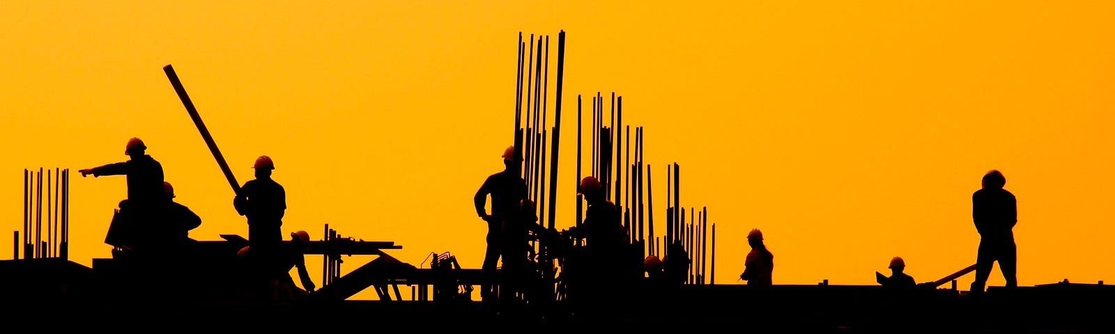 Men, a silluete of men, working on a construction site during sunset.