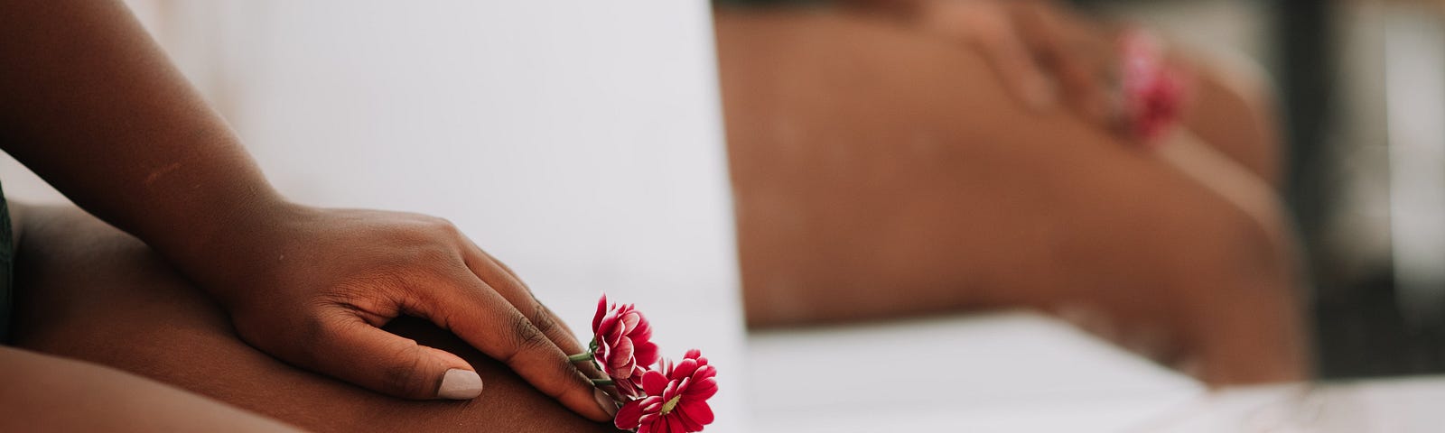 Unrecognizable black female legs and with flowers in hand