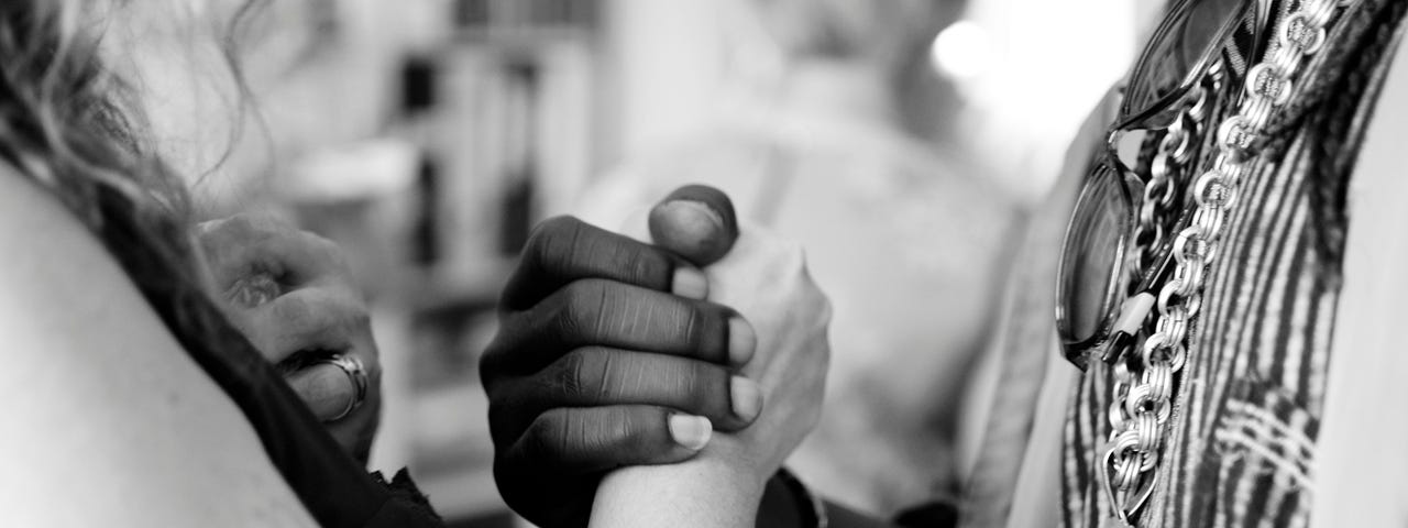 Two people, one white and one black, clasping hands