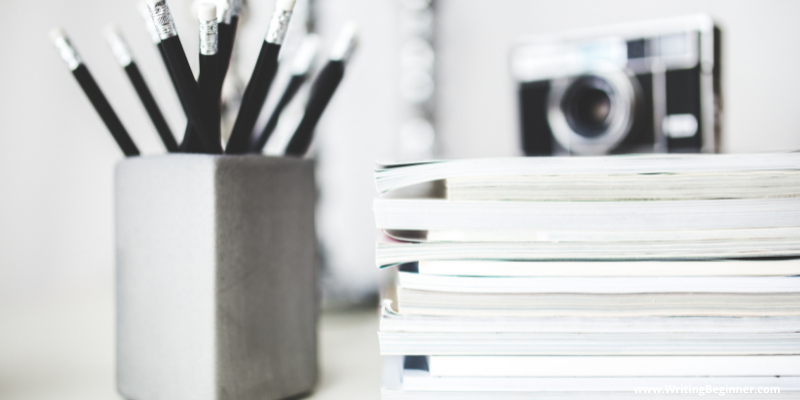 black and white photo of pencils, camera, and stack of books — Human Article Spinner