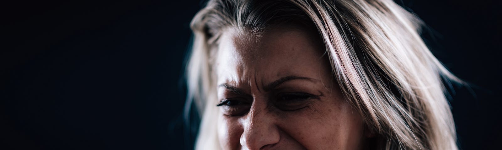 An woman with a mean face scowls and squeezes her fists in anger.