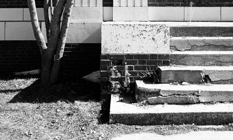 Concrete steps, cracked and spalled, falling apart due to decay.