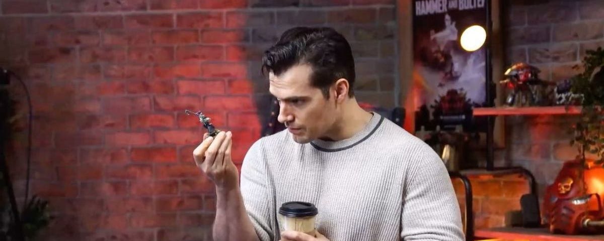 Henry Cavill inspects an unknown painted miniature figure at Warhammer World.
