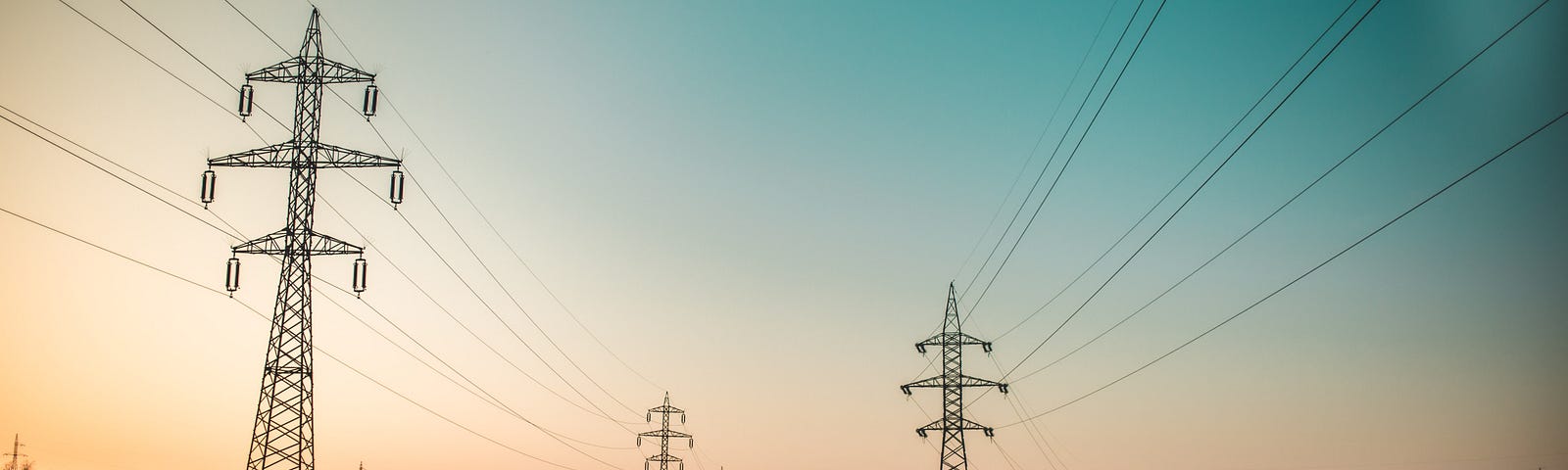 Transmission lines run along towers over a grassy field.