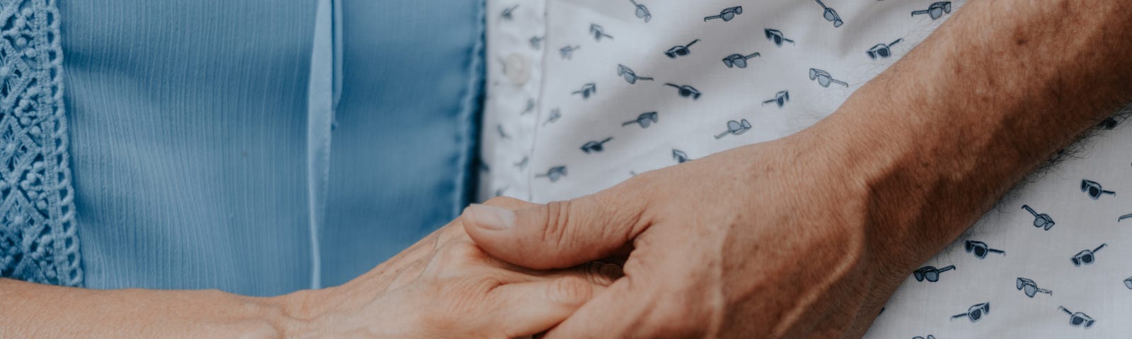 Two elderly people holding hands.