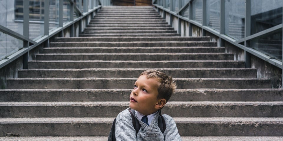 Estudante estoniano sentado em uma escada em frente à escola. Educação básica na Estônia é uma das melhores da Europa