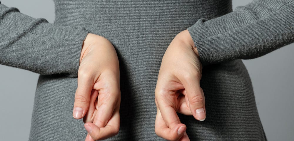 Woman talking untruth and holding her fingers crossed behind her back.