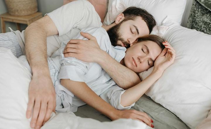 Photo of young couple in bed for humor article on health benefits of spooning in bed, but also forking and knifing positions. Health. Cancer. Medicine. Medical. Healing.