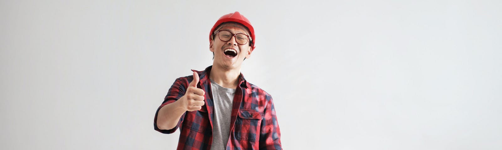 A smiling worker in a hard hat works with paper and a computer