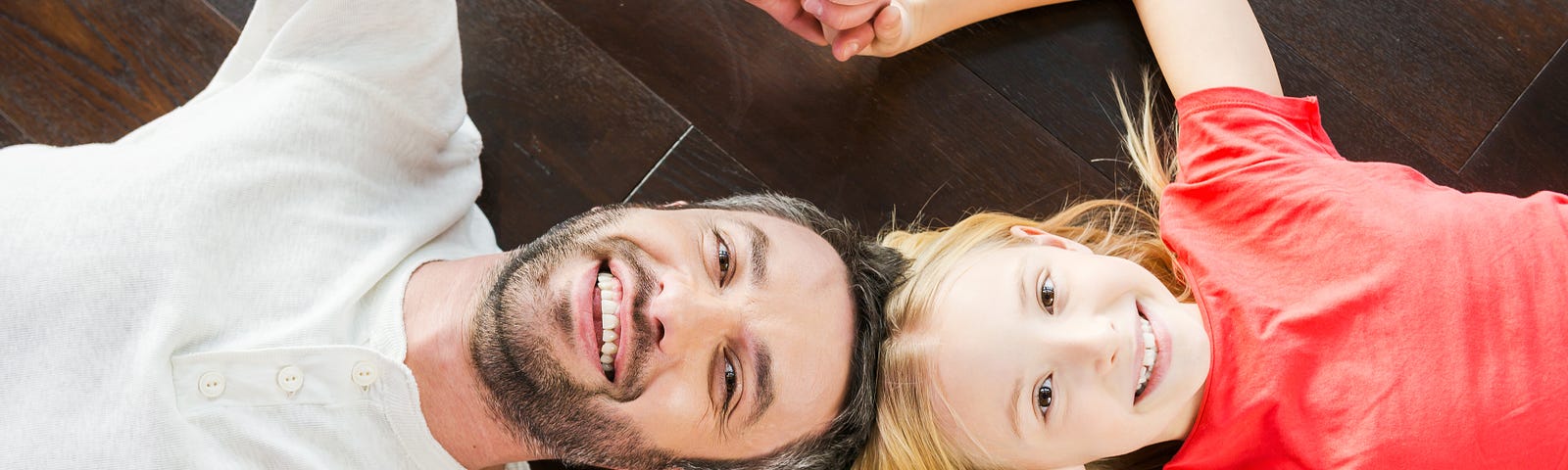 ADHD father with his ADHD daughter holding hands laying on the floor playing
