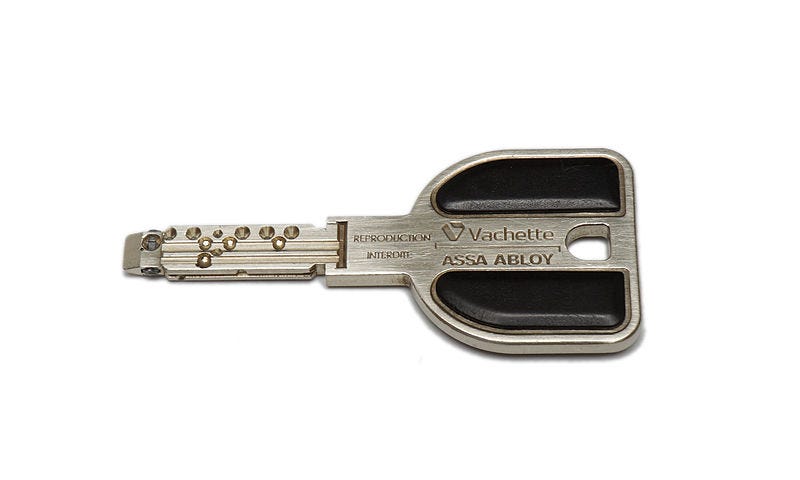 A photograph of a small silver key on a white background