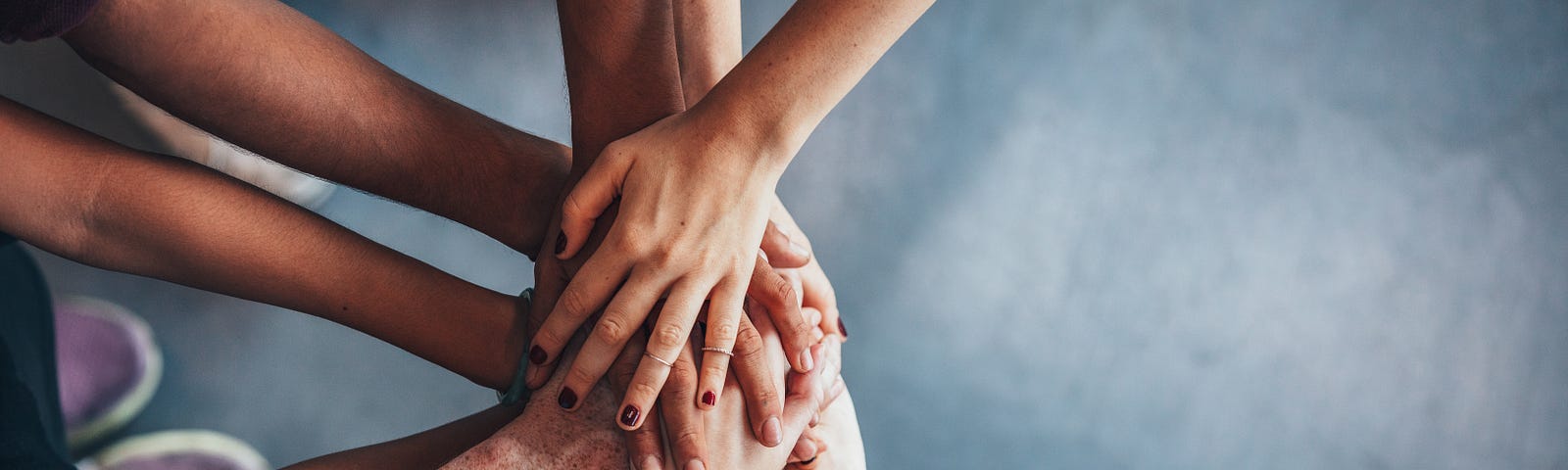 Overhead image of five pairs of hands piled on top of one another to signify teamwork.