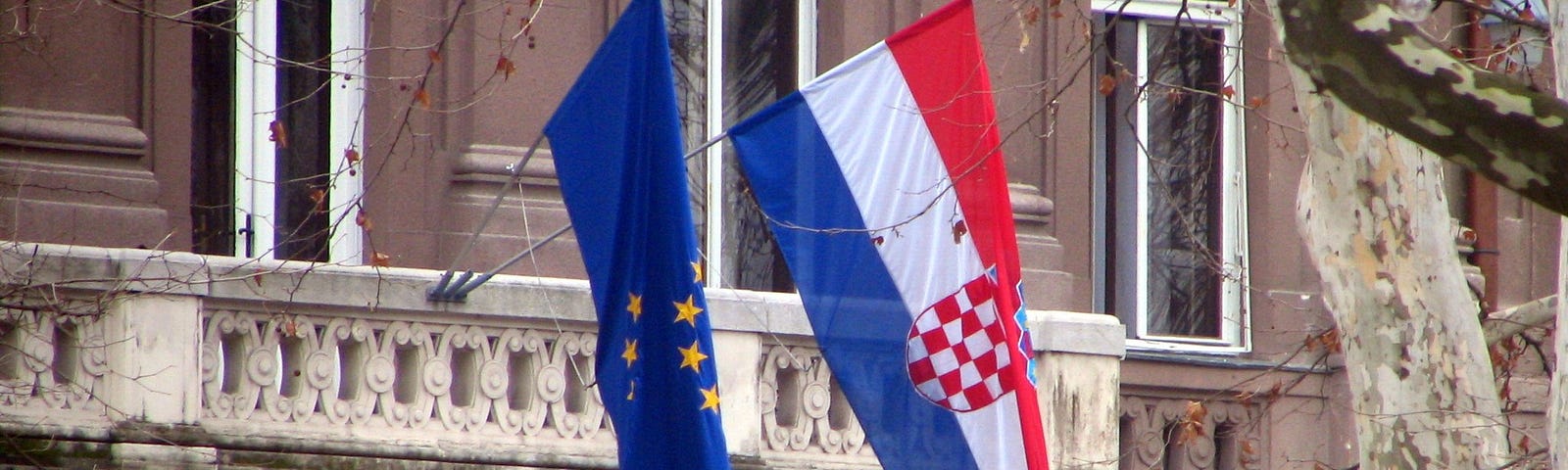 A Croatia flag and EU flag together outside a building