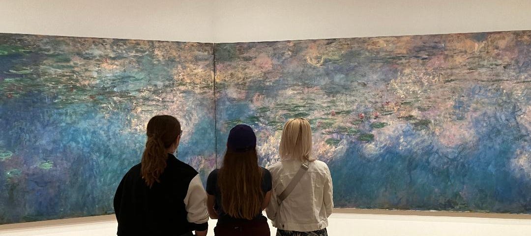 Three girls standing in front of Water Lilies at the Moma