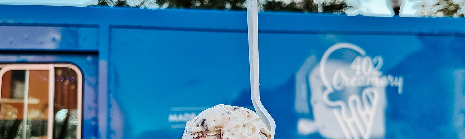 A scoop of 402 Creamery ice cream held up in front of their food truck